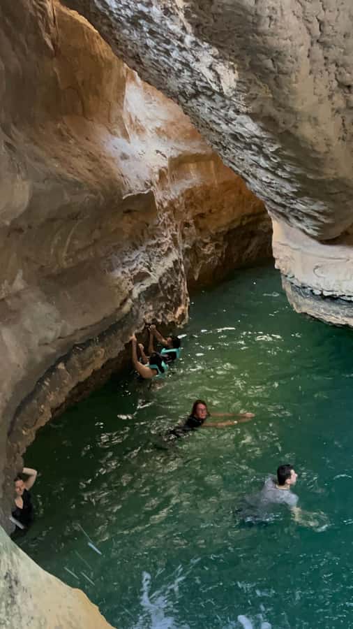 Muscat: Wadi Shab, Romantic Cave and Sinkhole Full-day Trip - Crossing the river into Wadi Shab